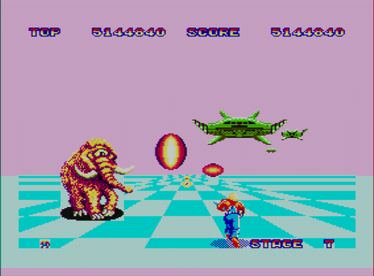 Captura del videojuego Space Harrier. En la parte inferior vemos al protagonista corriendo hacia el fondo sobre un terreno azul . A la izquierda hay un mamut lanudo con un solo ojo. En el centro unos disparos y lo que parecen unas naves espaciales de color verde.