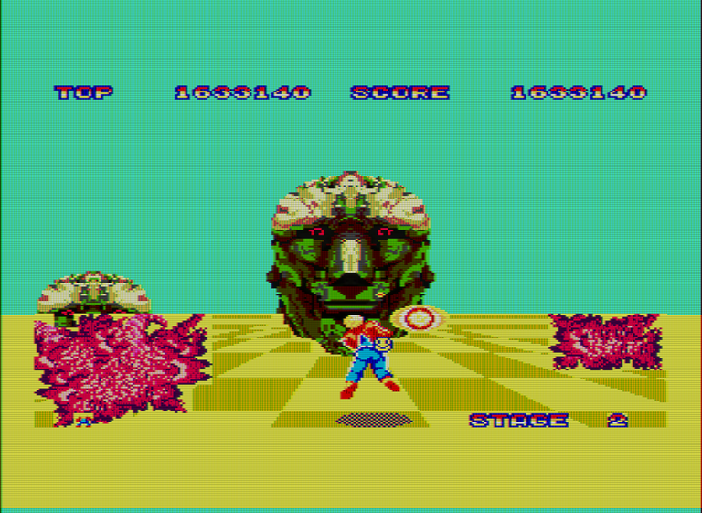 Captura del videojuego Space Harrier. Una gigantesca cara de roca con un par de ojos rojos ataca al protagonista